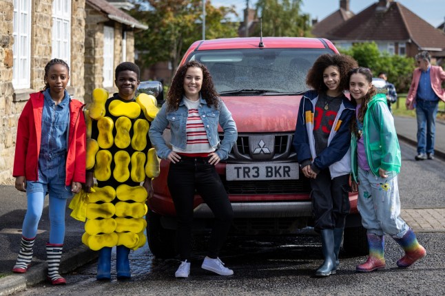 Dani Harmer and four teen actors stand around a Mitsubishi truck