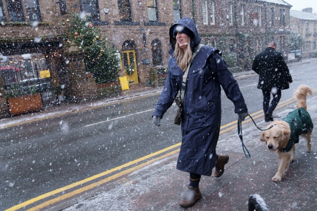 A woman walks through heavy snowfall on the high street of Saddleworth, England, Tuesday, Jan. 7, 2025.(AP Photo/Jon Super)