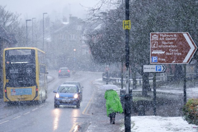 A woman walks trough heavy snowfall on the high street of Saddleworth, England, Tuesday, Jan. 7, 2025.(AP Photo/Jon Super)