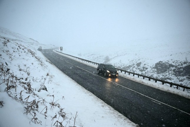 A car is driven along the snow-covered Woodhead pass between Woodhead and Homlfirth, in the Peak District in northern England on January 7, 2025, after snow and rain continued to fall across parts of the United Kingdom. (Photo by Oli SCARFF / AFP) (Photo by OLI SCARFF/AFP via Getty Images)