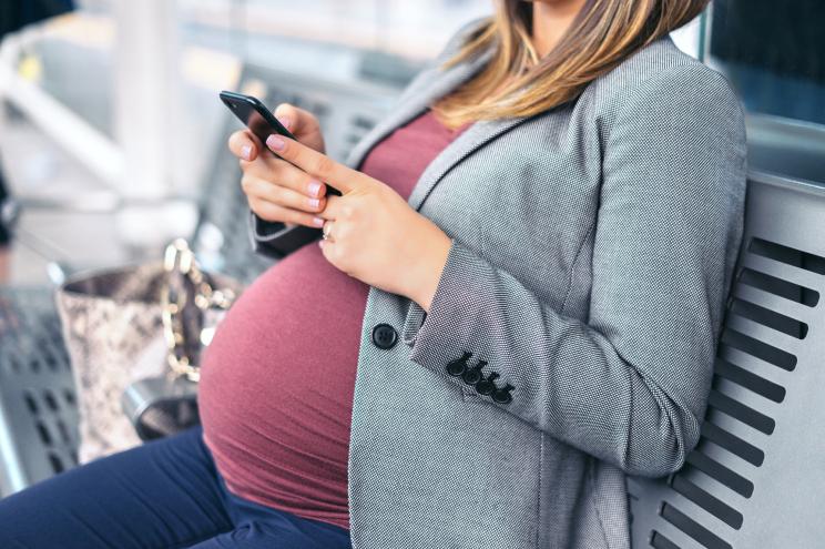 Pregnant woman on the phone while waiting for a train