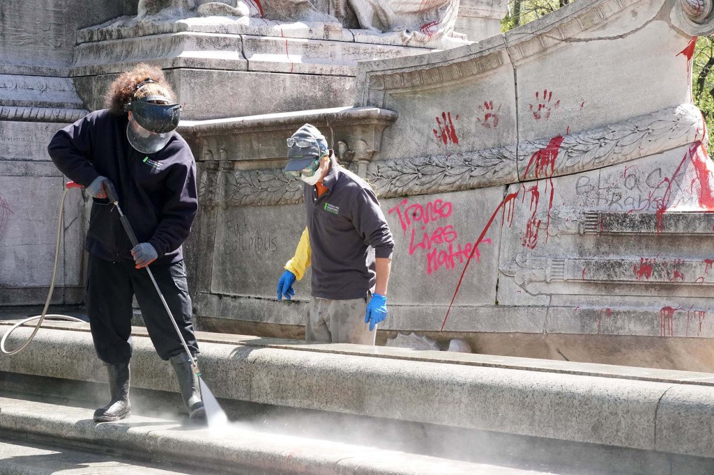 Crews work to remove graffiti from the USS Maine statue near Columbus Circle.