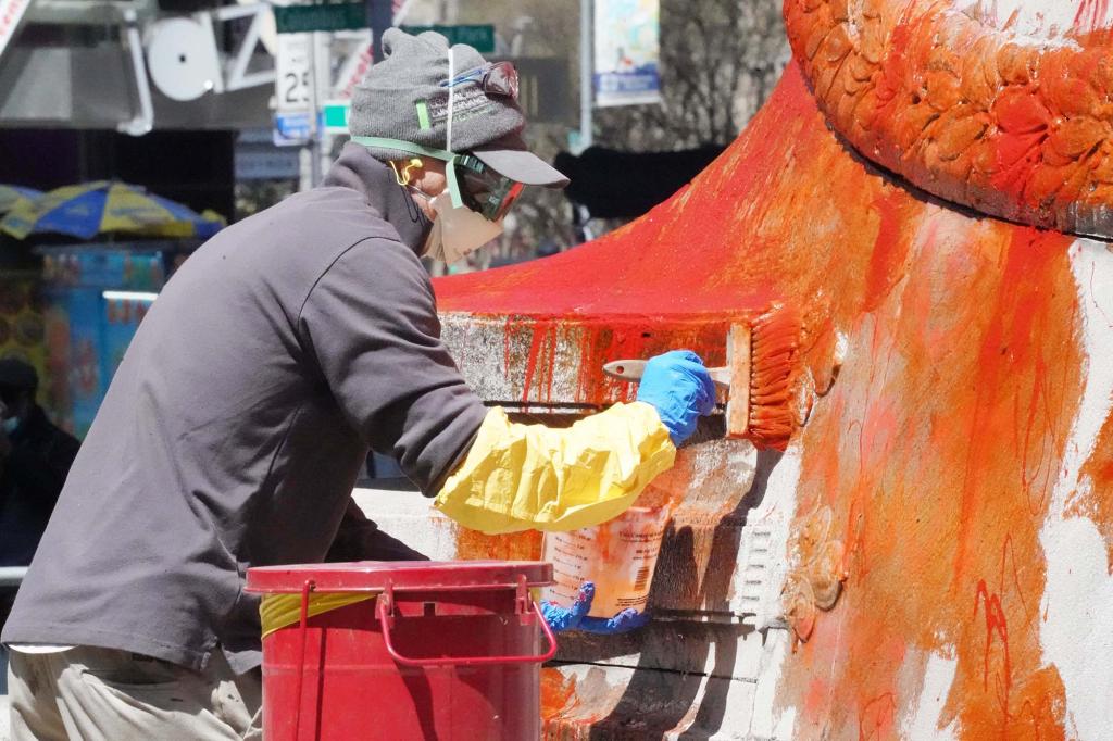 A worker brushes a chemical onto the stone before washing off the paint.