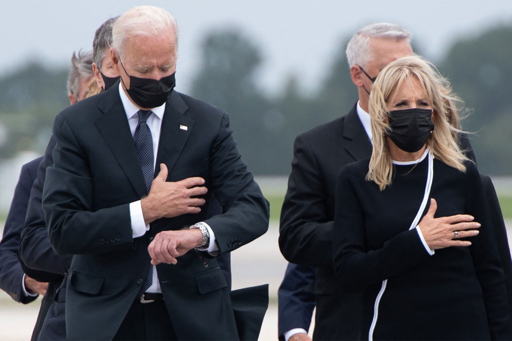 US President Joe Biden looks down alongside First Lady Jill Biden as they attend the dignified transfer of the remains of a fallen service member at Dover Air Force Base.