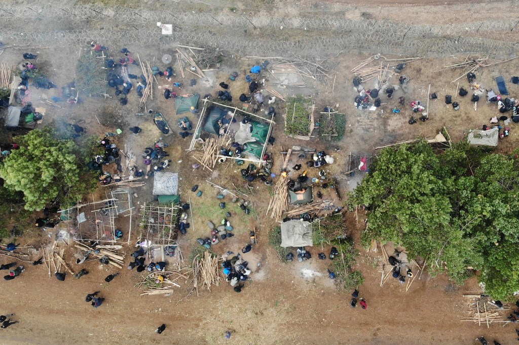 Migrants collect their belongings before leaving a camp on the Belarusian-Polish border in the Grodno region and heading towards the Polish Kuznica border.