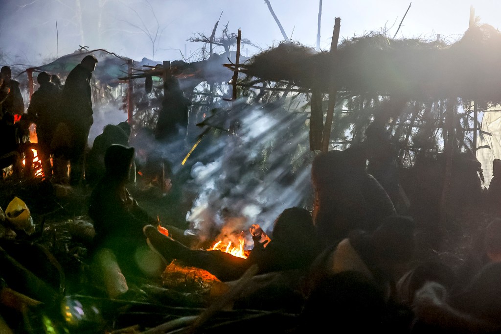 Migrants warm themselves near a fire as they gather at the Belarus-Poland border near Grodno.