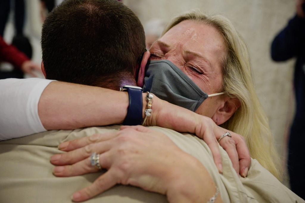 Alison Henry embraces her son Liam as they meet after arriving on a flight from the UK