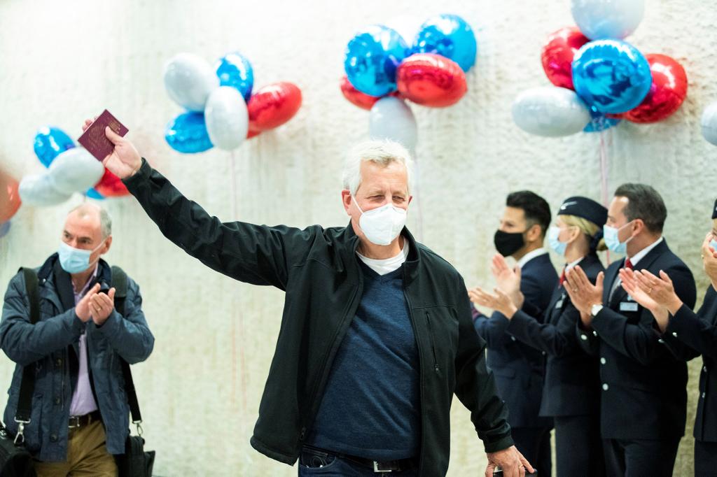 A man waves to the crowd as he exits baggage claim