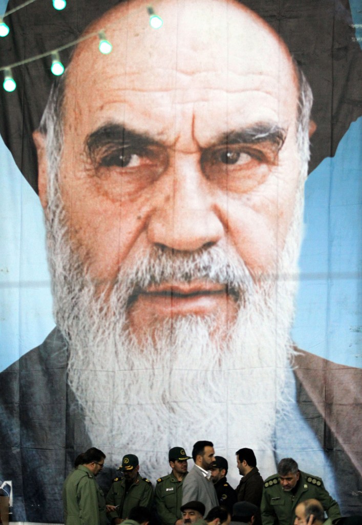 Men in front of a portrait of Ayatollah Khomeini.