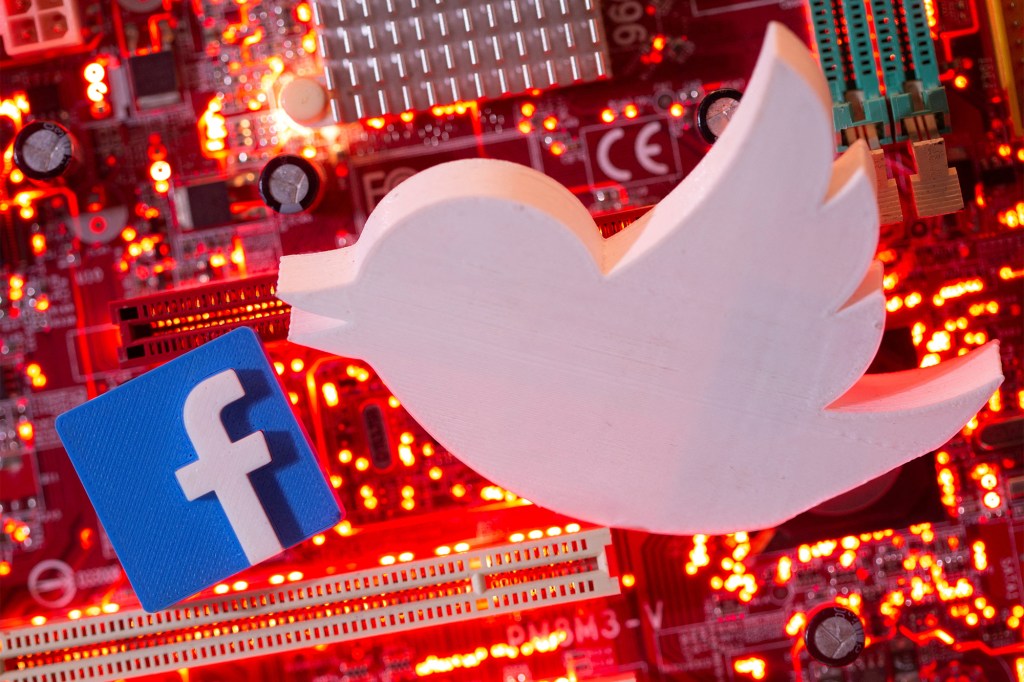 3D printed Facebook and Twitter logos are placed on a computer motherboard