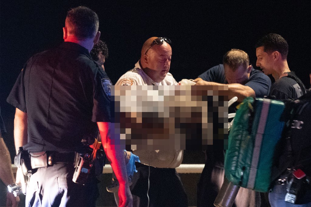 First responders carry one of Erin Merdy's children (whose body has been blurred) off the beach at night.