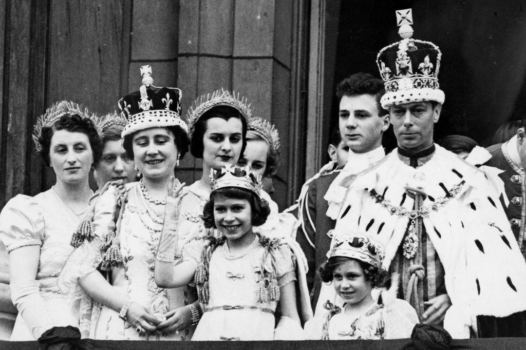 King George VI and Queen Elizabeth wear their coronation robes while Princess Elizabeth and Margaret wave on the balcony of Buckingham Palace on May 12, 1937.