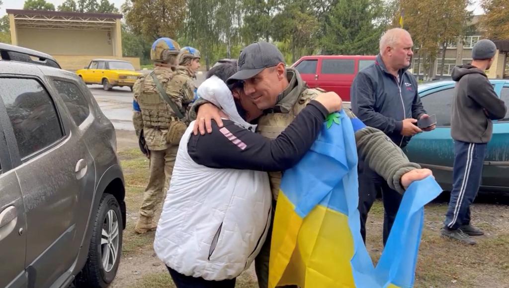 Derhachi District Mayor Vyacheslav Zadorenko embraces a resident while holding a Ukrainian Flag in Kharkiv Region, Ukraine.