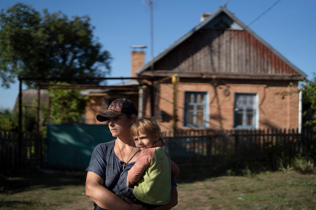 Natalia Stokoz holds her daughter Veronika, 3, as they stand in front of their house in the village of Zorya.