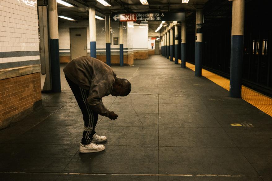 a picture of a homeless man picks up items at the B,D, F, M Bleeker st subway station in Manhattan.