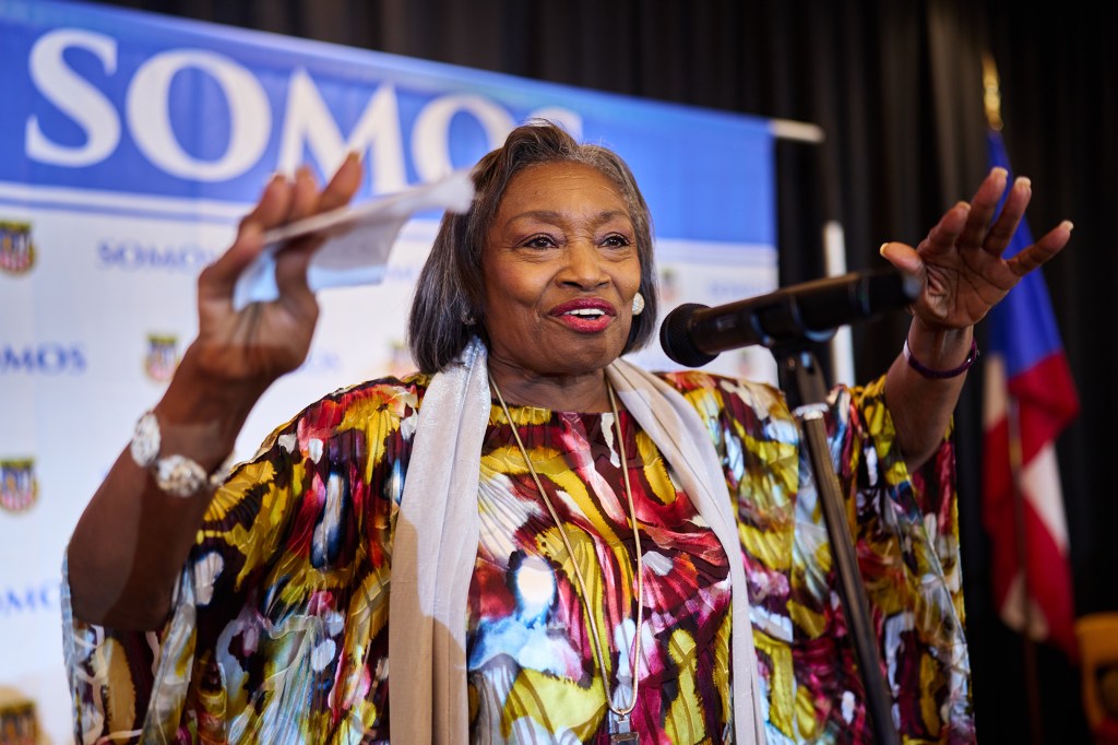 A woman standing at a microphone with raised arms.