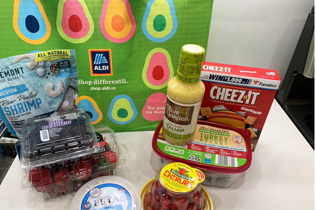 A green Aldi bag and groceries on a white counter