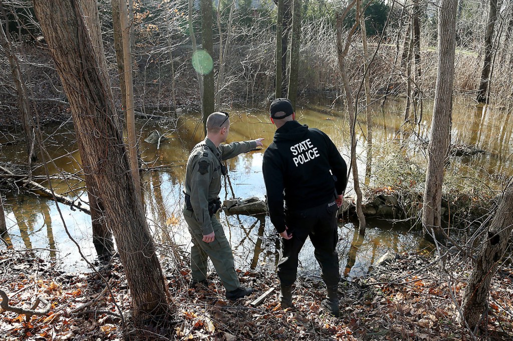 A Massachusetts Environmental Police officer points out something to a state trooper in the swamps across the street from the Walshe home in Cohasset on Saturday, Jan. 7, 2023.