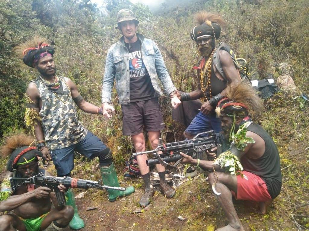 In this undated photo released by West Papua Liberation Army, the armed wing of the Free Papua Movement, Papuan separatist rebels pose for a photo with a man they said is New Zealander pilot Phillip Mark Mehrtens.