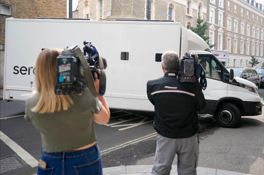 Journalists film a prison van moving into Westminster Magistrates Court in London.