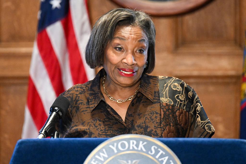 Andrea Stewart-Cousins speaking at a podium in front of a wooden background.