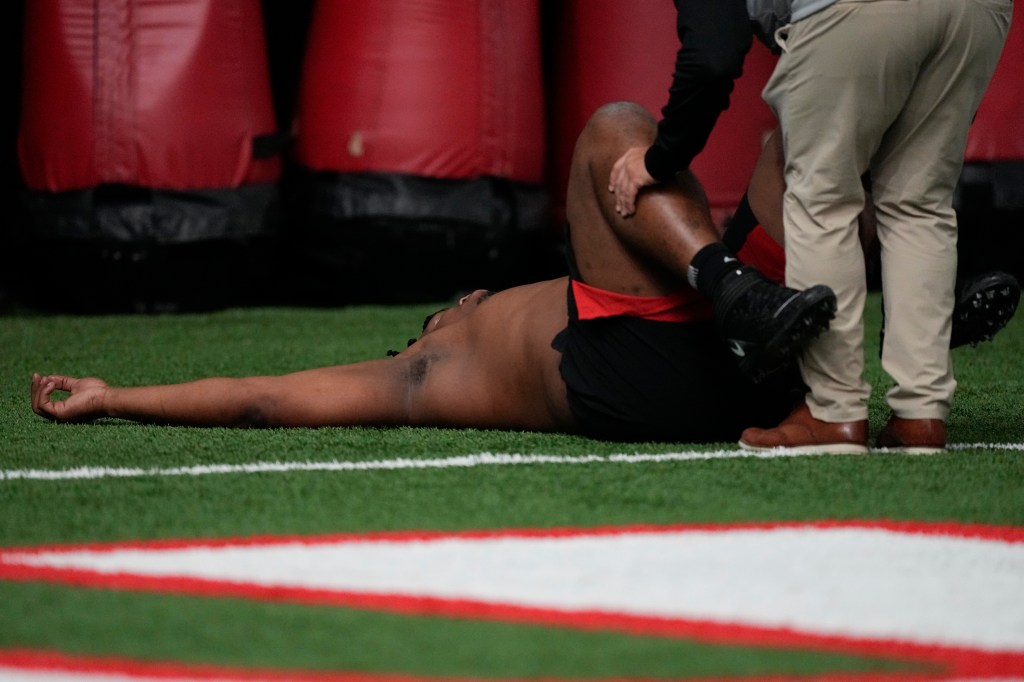 A trainer works with former Georgia defensive lineman Jalen Carter after he runs football drills during Georgia's Pro Day, on March 15, 2023 in Athens, Ga.