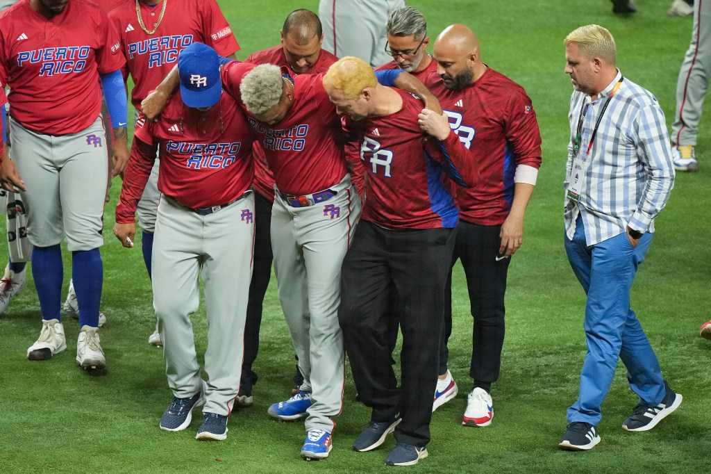 Edwin Diaz of Puerto Rico is helped off the field after being injured during the on-field celebration after defeating the Dominican Republic during the World Baseball Classic Pool D.