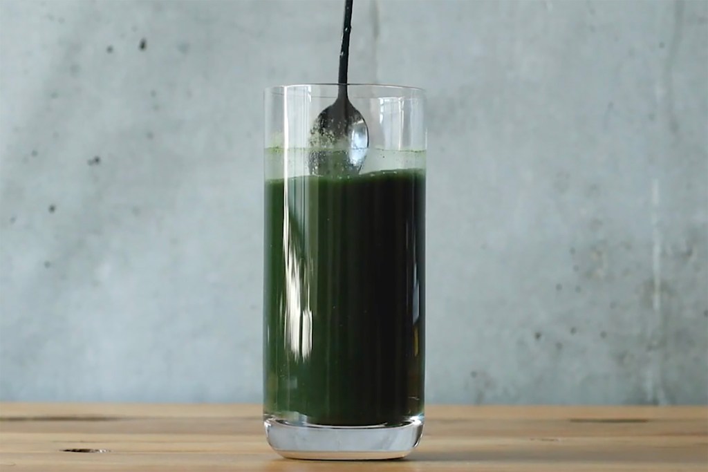 A spoon in a glass of green liquid