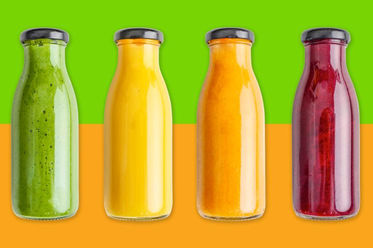 Several difference bottles of juice on a dual colored background.