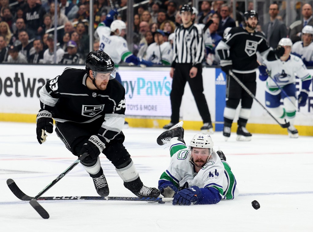 Kyle Burroughs #44 of the Vancouver Canucks dives for the puck next to Viktor Arvidsson #33 of the Los Angeles Kings