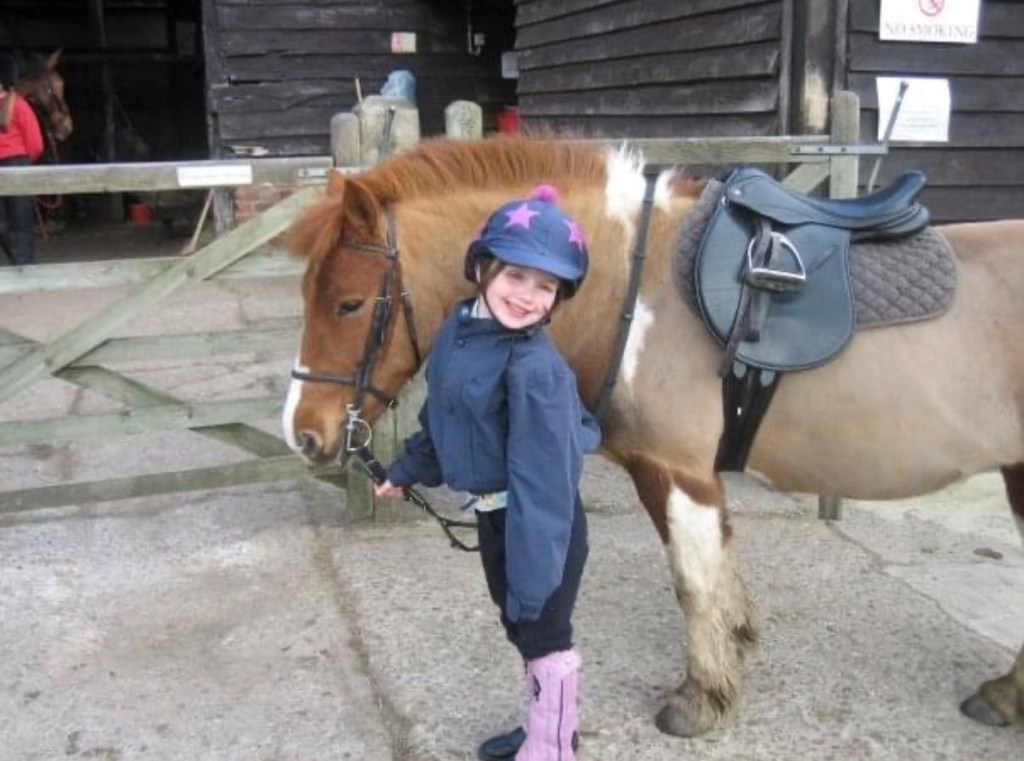 Small girl standing near horse.