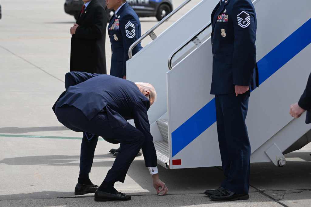 President Biden picks a challenge coin he dropped after landing at Minneapolis-Saint Paul International Airport Monday, April 3, 2023. 