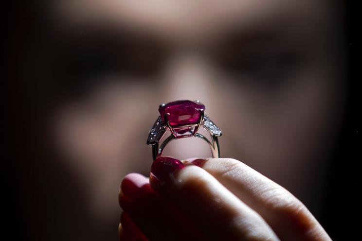 An employee of Sotheby's auction house poses with "The Sunrise Ruby", a rare Burmese ruby weighing 25.59 carats and estimated to sell for $12-18 million, during a press preview in London on April 8, 2015.