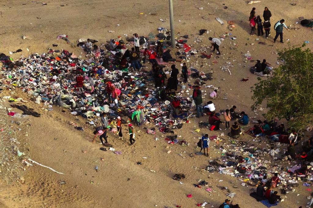 Migrants who crossed the U.S.-Mexico border gather by the U.S. Border Wall as they wait to be processed.