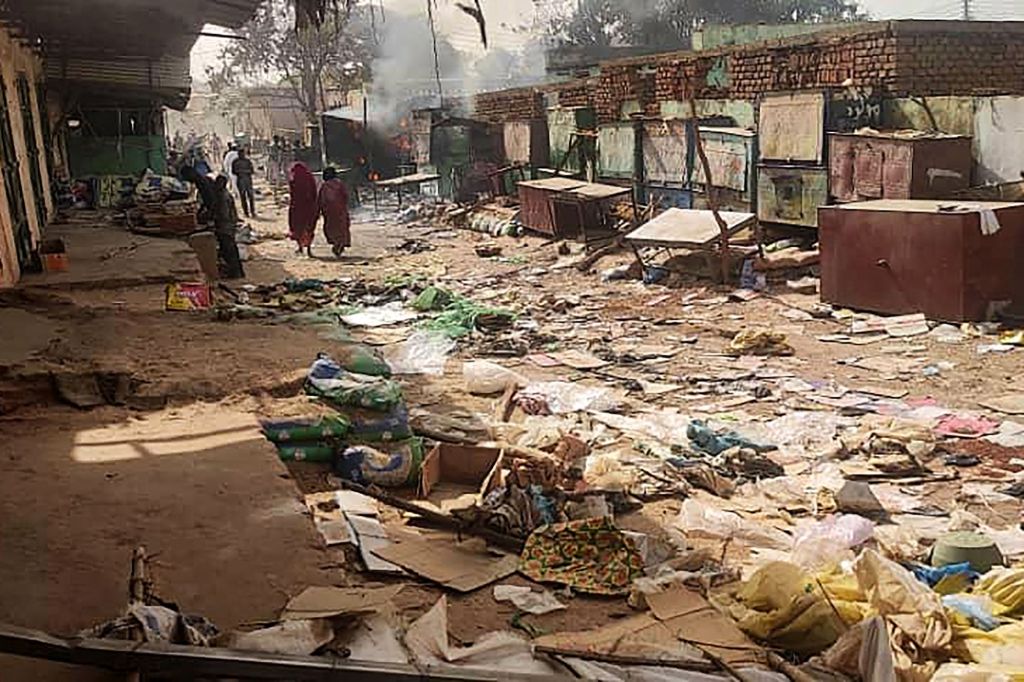 People walk among scattered objects in the market of El Geneina after forces clashed.