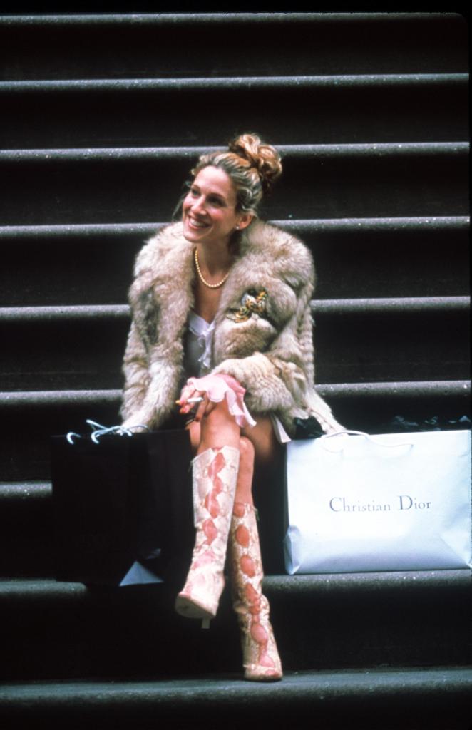 Sarah Jessica Parker, as Carrie Bradshaw in "Sex and the City," sitting on stairs with a Christian Dior shopping bag