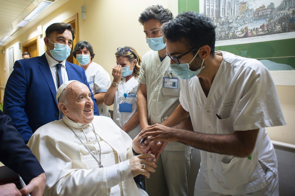 Pope Francis is greeted by hospital staff as he sits in a wheelchair inside the Agostino Gemelli Polyclinic in Rome, on July 11, 2021. 