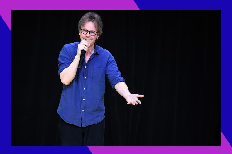 Dana Carvey speaks into a microphone while performing onstage.