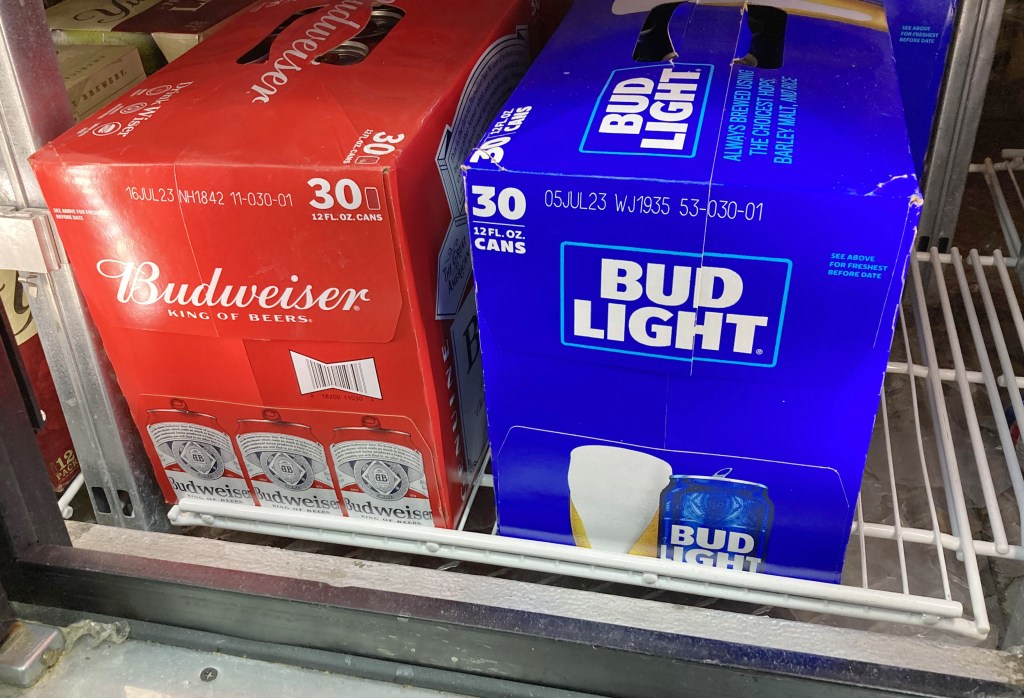 two cases of Bud Light and Budweiser on a refrigerated shelf.