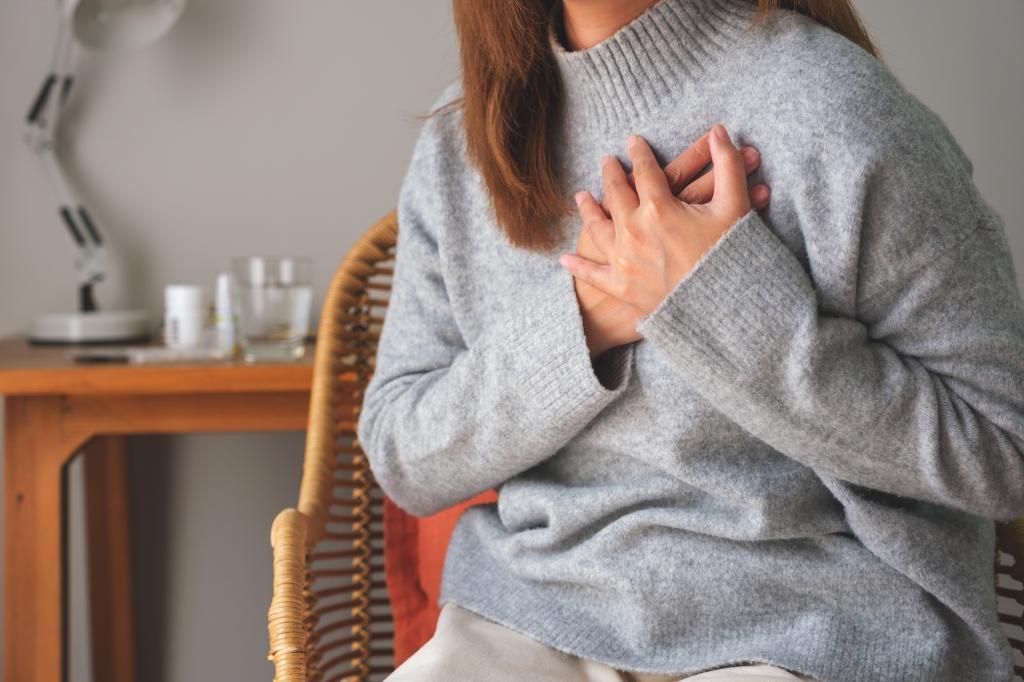 Closeup image of a woman with hands on chest, sudden heart attack, suffering from chest pain