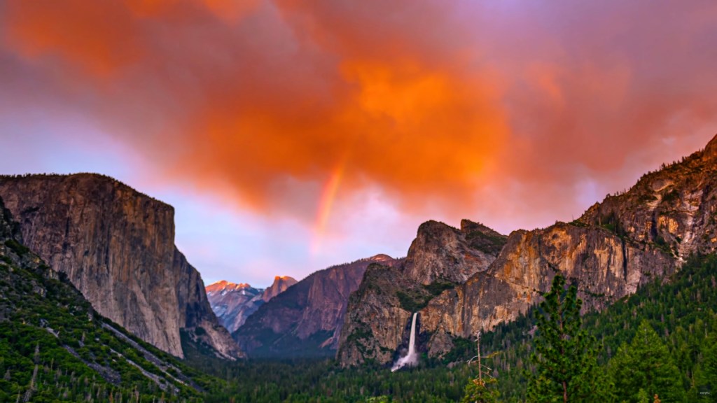 Red-tinged rainbow above Half Dome peak.