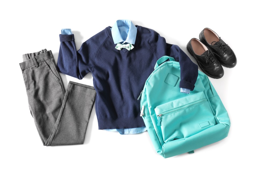 Stylish school uniform for boy and backpack on white background.