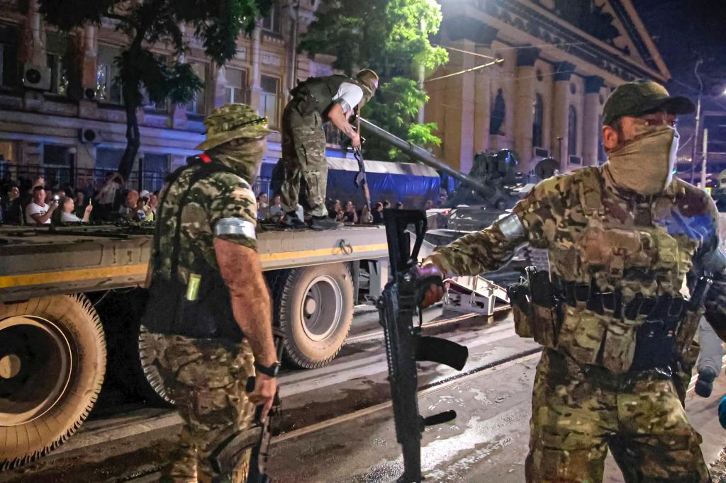 Members of the Wagner Group military company guard an area as other load their tank onto a truck on a street in Rostov-on-Don, Russia, Saturday, June 24, 2023