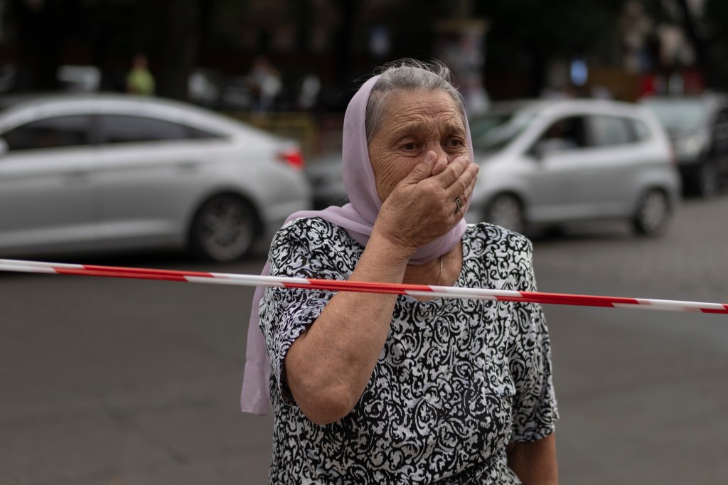 pictured is a woman reacting as she stands outside the Odesa Transfiguration Cathedral after a missile hit