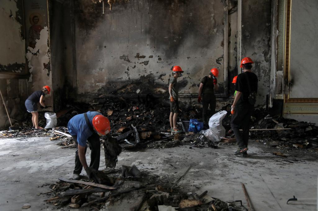 Workers are pictured picking through the rubble after the attack, trying to salvage what they could. 