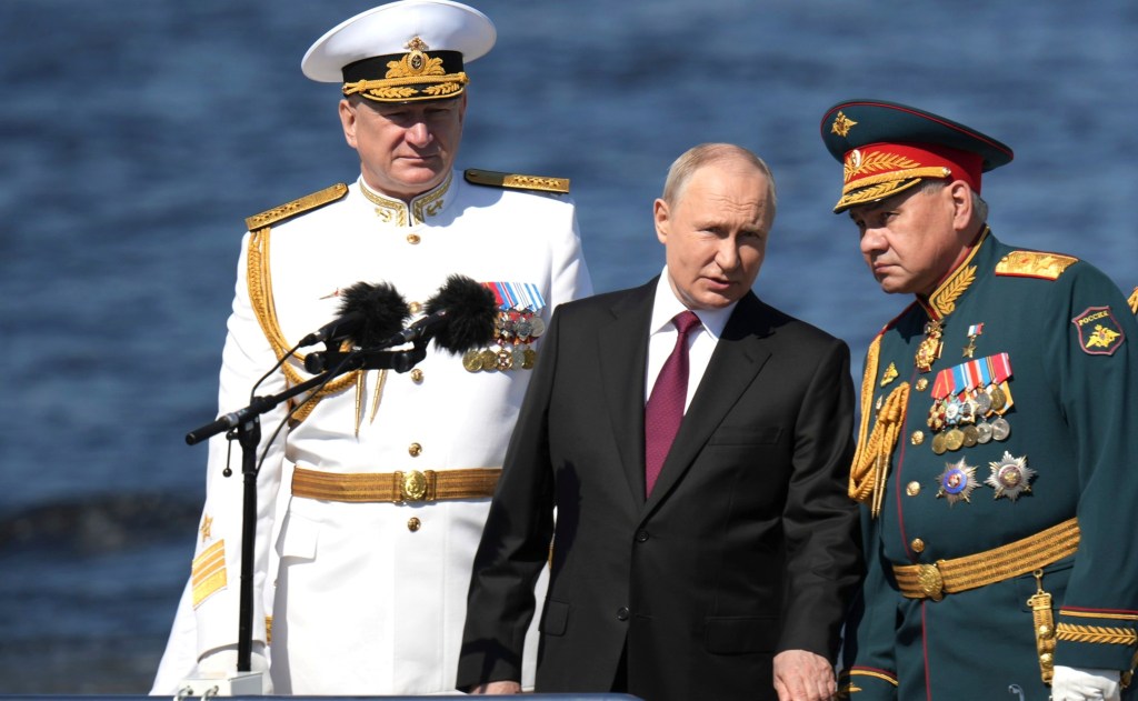 Russian President Vladimir Putin, center, reviews the parade of naval vessels accompanied by Russian Defence Minister Sergei Shoigu, right, and Naval Commander Nikolai Yevmenov, left, onboard the naval cutter Raptor on the Neva River, July 30, 2023 in St. Petersburg, Russia. 