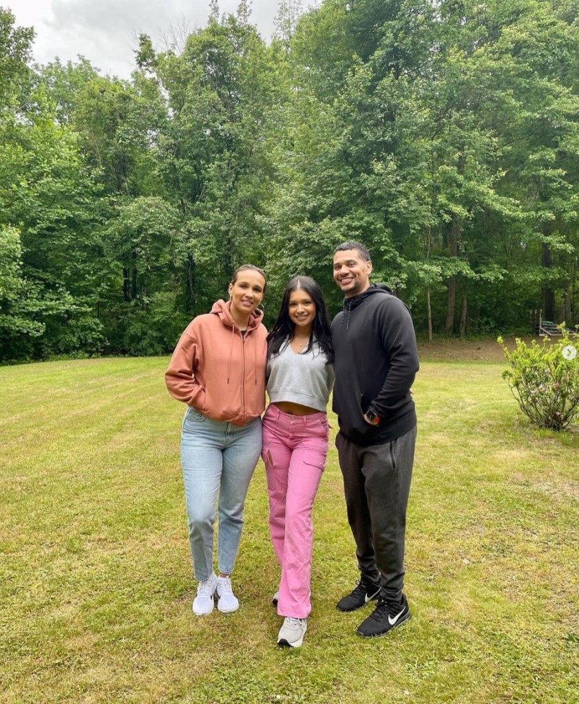 A photo of three people, including an unnamed woman on the left, Tiara Wheeler in the center and her father, former NBA player Tyson Wheeler, on the right.