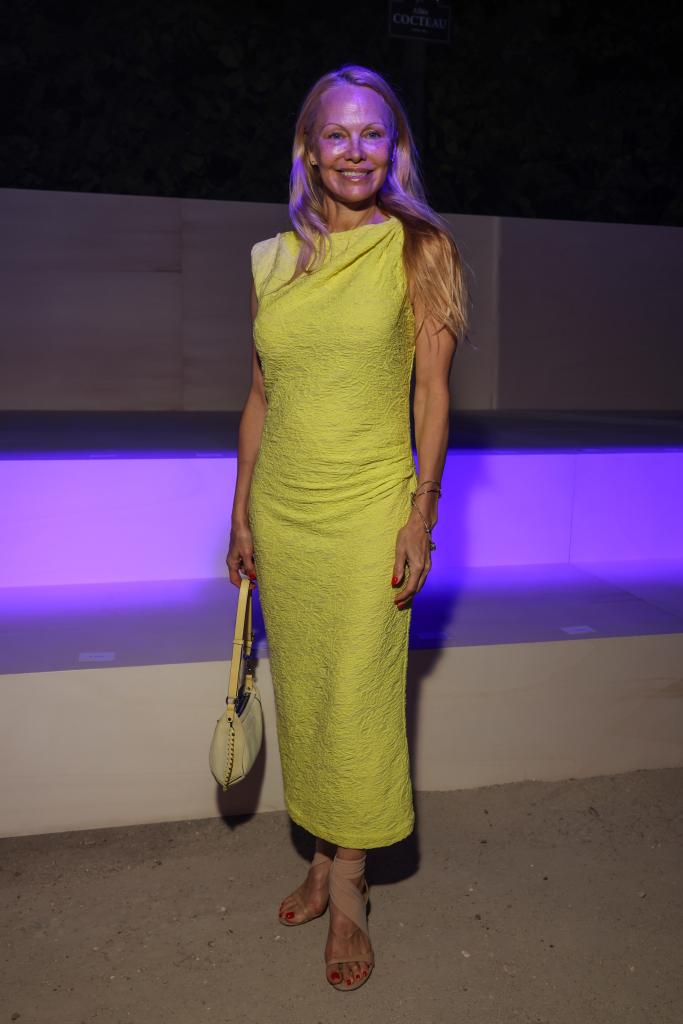 Photo of Pamela Anderson wearing a sleeveless yellow maxi dress. 