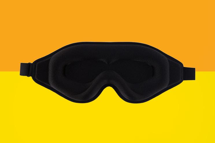 Black sleep mask on an orange and yellow background.