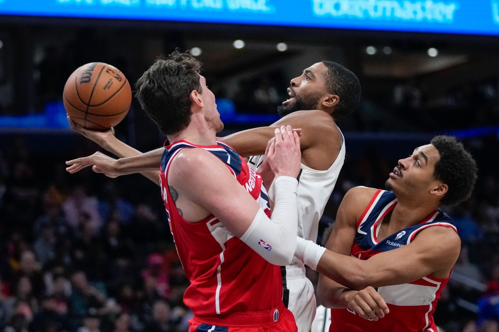 Mikal Bridges, center, shoots from between Washington Wizards center Mike Muscala, left, and guard Jordan Poole during the first half.